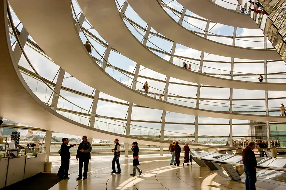 People walk along a four-story walkway inside a glass building, demonstrating how you can go farther with our payments and fintech expertise.